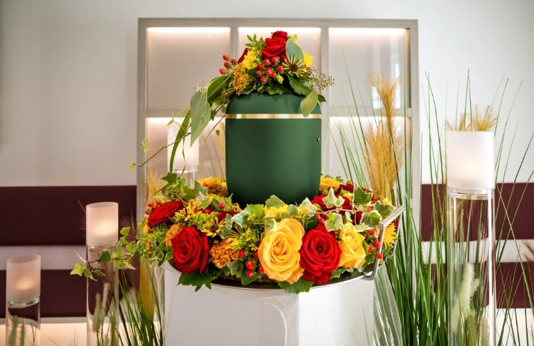 zielona urna otoczona kwiatami